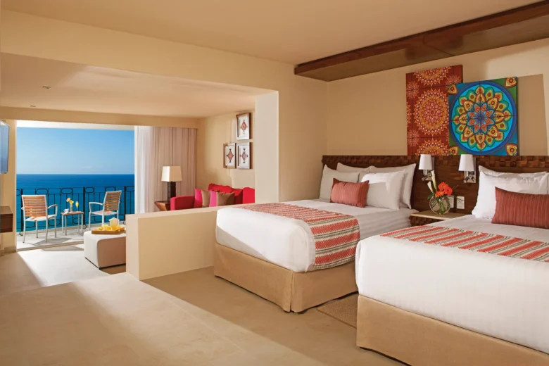 Sun Club Junior Suite Ocean Front with two double beds, semi-private living area, and ocean view balcony at Sunscape Puerto Vallarta Resort & Spa.