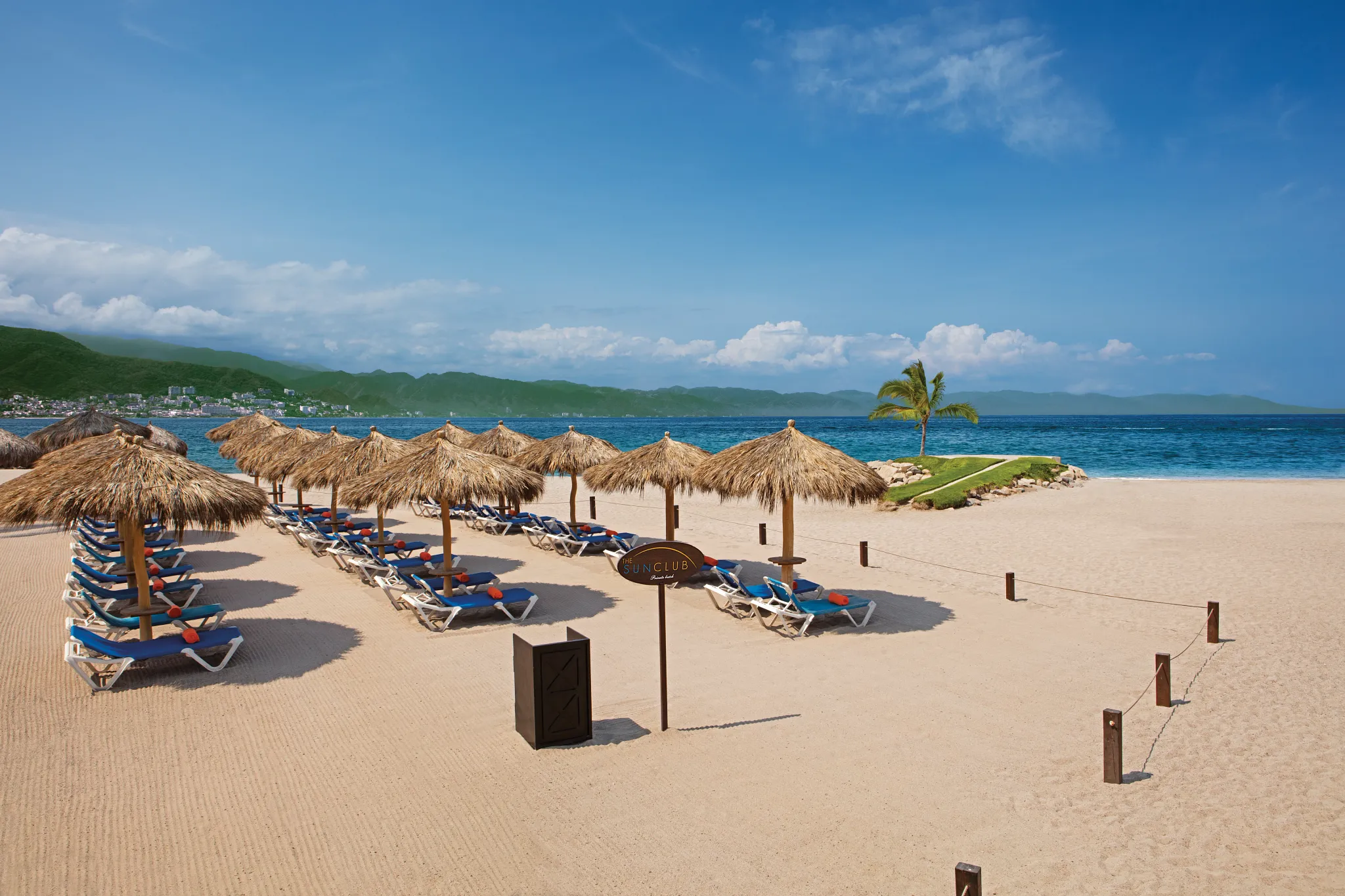 Sun Club beachfront area at Sunscape Puerto Vallarta Resort & Spa with palapa umbrellas, lounge chairs, and ocean views.