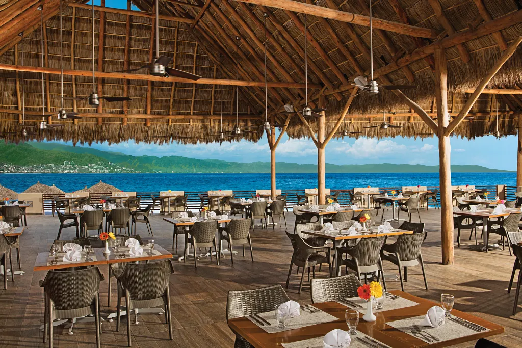 World Café at Sunscape Puerto Vallarta Resort & Spa featuring an open-air oceanfront buffet restaurant with thatched roof, spacious seating, and panoramic sea views.